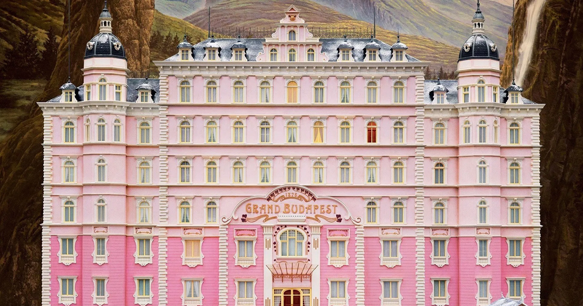 تصویری از هتل بزرگ بوداپست، ساختمانی صورتی و زیبا با معماری کلاسیک اروپایی در میان کوه‌های برفی